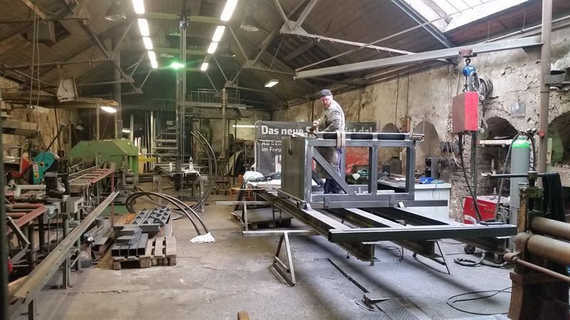 Ein Mann arbeitet in einer Fabrik an einer Metallkonstruktion.