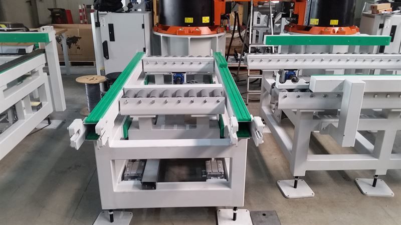 In einer Lagerhalle steht neben einer Maschine ein Förderband.