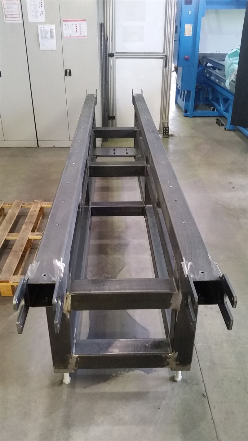 In einem Lagerhaus steht eine lange Metallkonstruktion auf einem Betonboden.