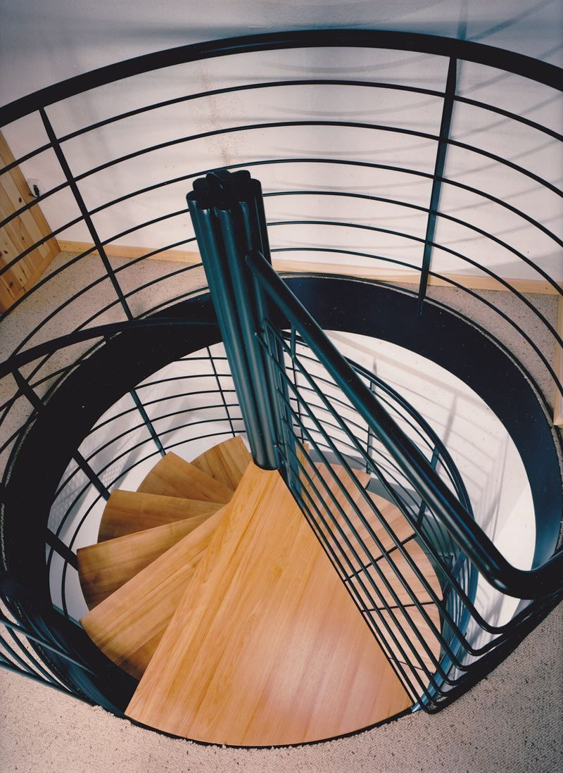 Eine Wendeltreppe mit schwarzem Geländer und Holzstufen