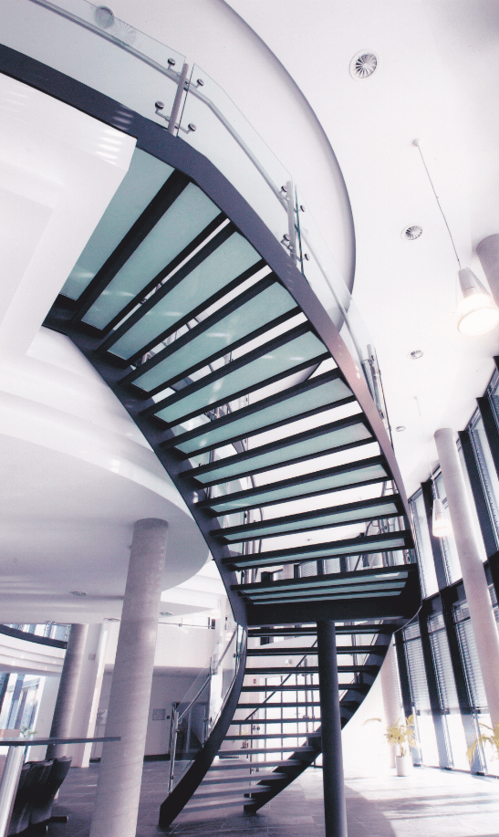 Eine geschwungene Treppe mit einem Glasgeländer in einem Gebäude