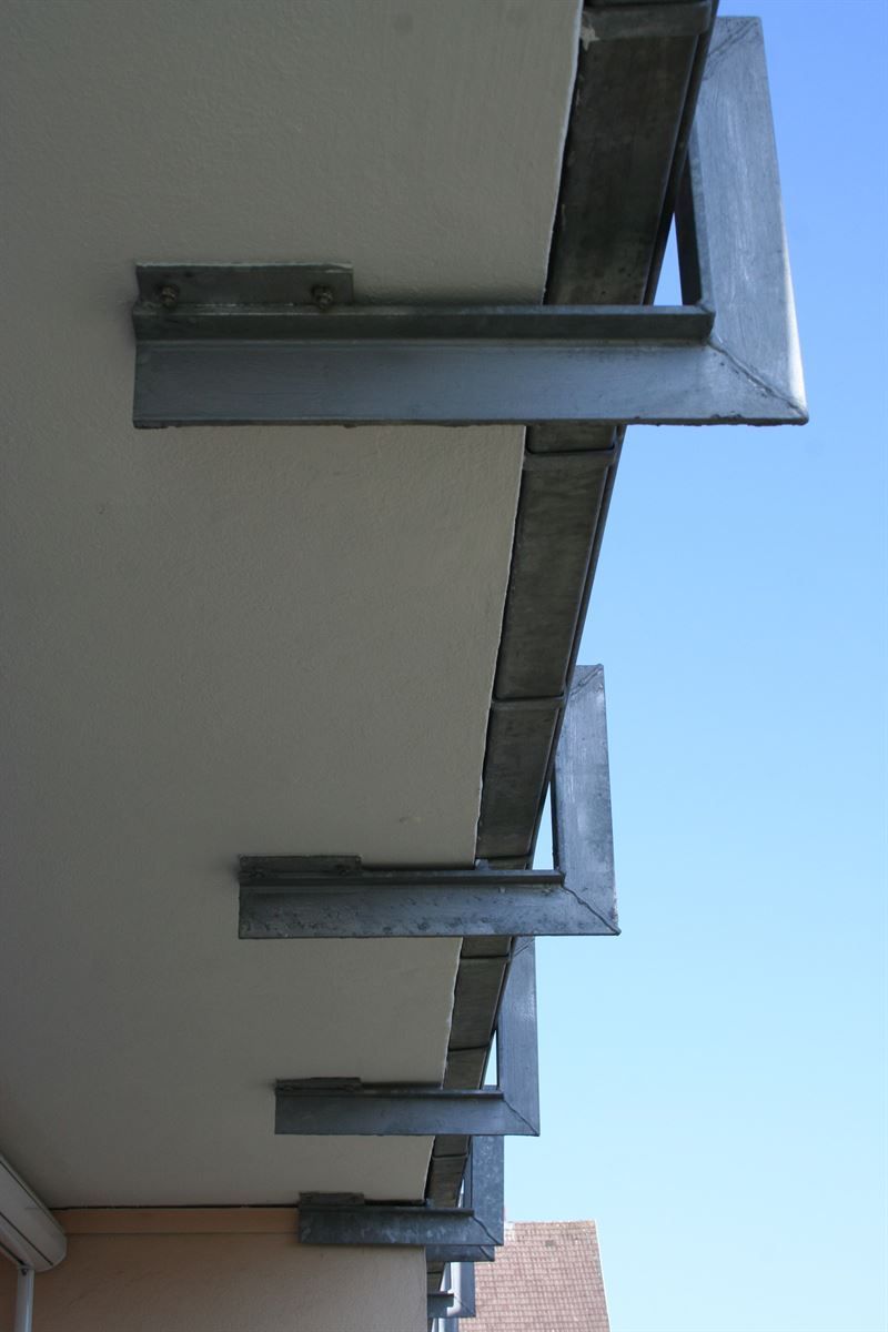 Ein Balkon an einem Gebäude mit einem blauen Himmel im Hintergrund.