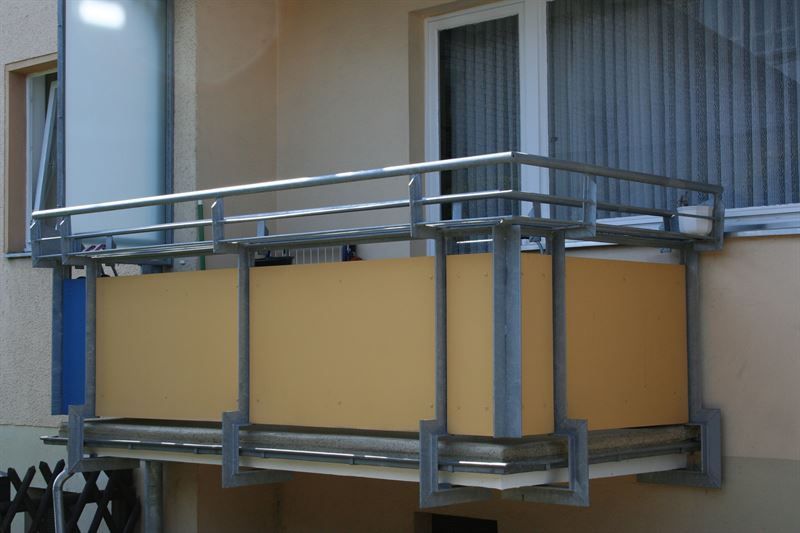 Ein gelber Balkon mit einem Metallgeländer an der Seite eines Gebäudes