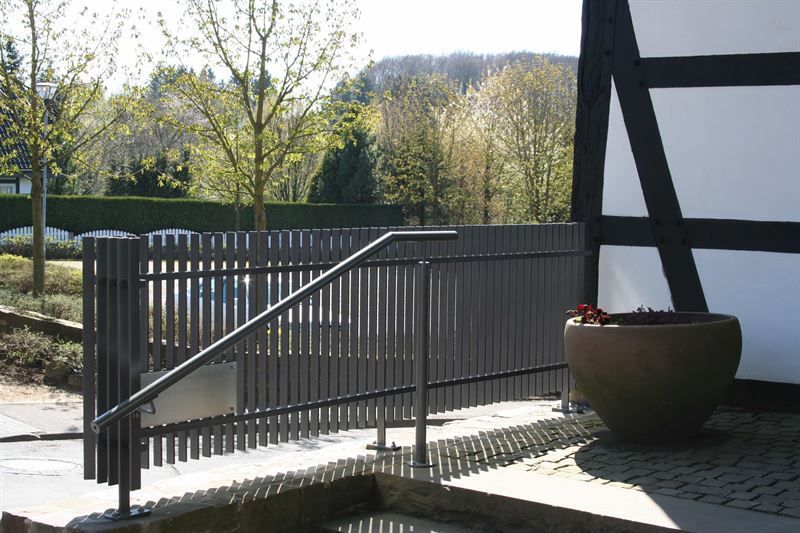 Ein Zaun mit Geländer und einer Topfpflanze davor