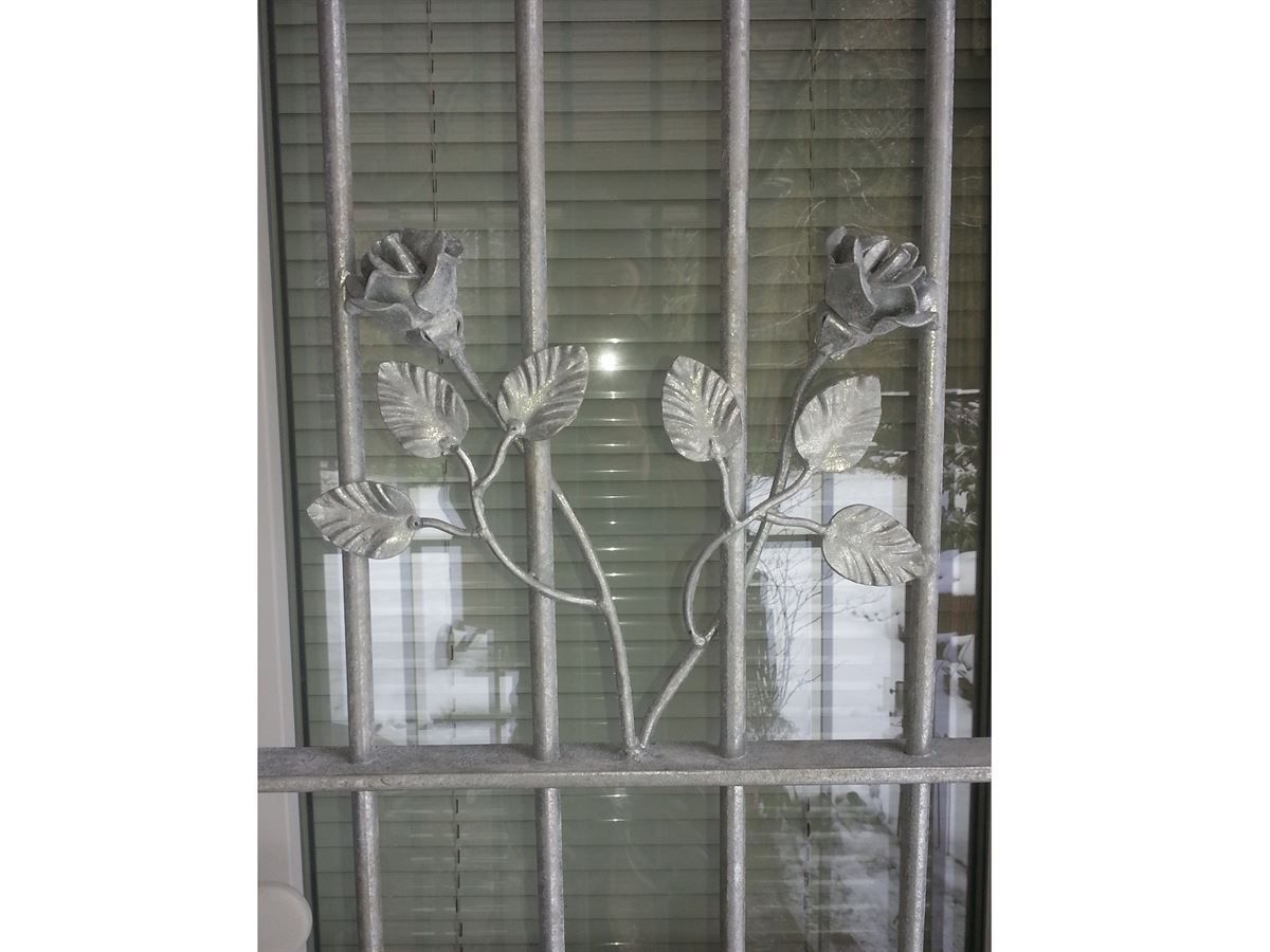 Eine Nahaufnahme eines schmiedeeisernen Tores mit Blumen und Blättern darauf.