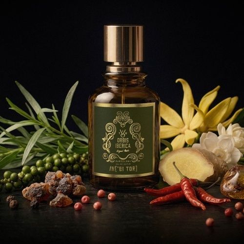 Frasco de perfume color ámbar con tapón y etiqueta dorados. La etiqueta presenta texto y elementos de diseño dorados.