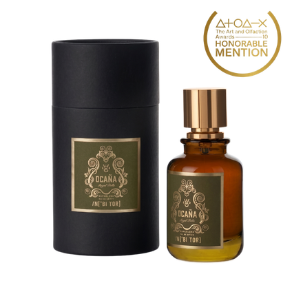 Un frasco de perfume y una caja cilíndrica. El frasco es marrón con un tapón dorado. La caja es negra.
