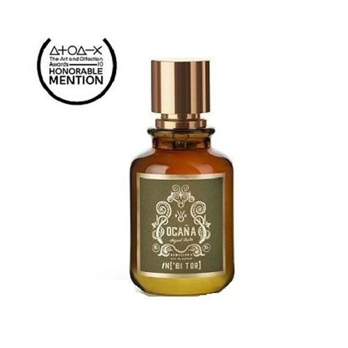 Frasco de perfume marrón con tapón dorado y etiqueta que dice "OCANA". Tiene el logo de "Mención Honorífica" en la esquina superior izquierda.