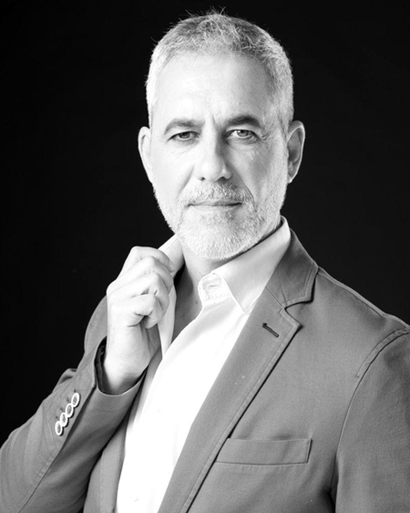 Hombre con blazer ajustándose el cuello, mirando a la cámara.