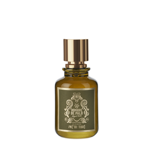 Un frasco de perfume de color verde oliva con tapón dorado y etiqueta en un marco verde oscuro.