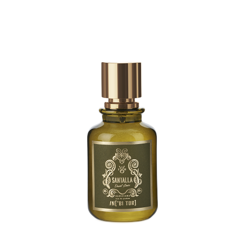 Frasco de perfume con tapón dorado y cristal tintado en verde. Etiqueta negra con texto dorado que dice 