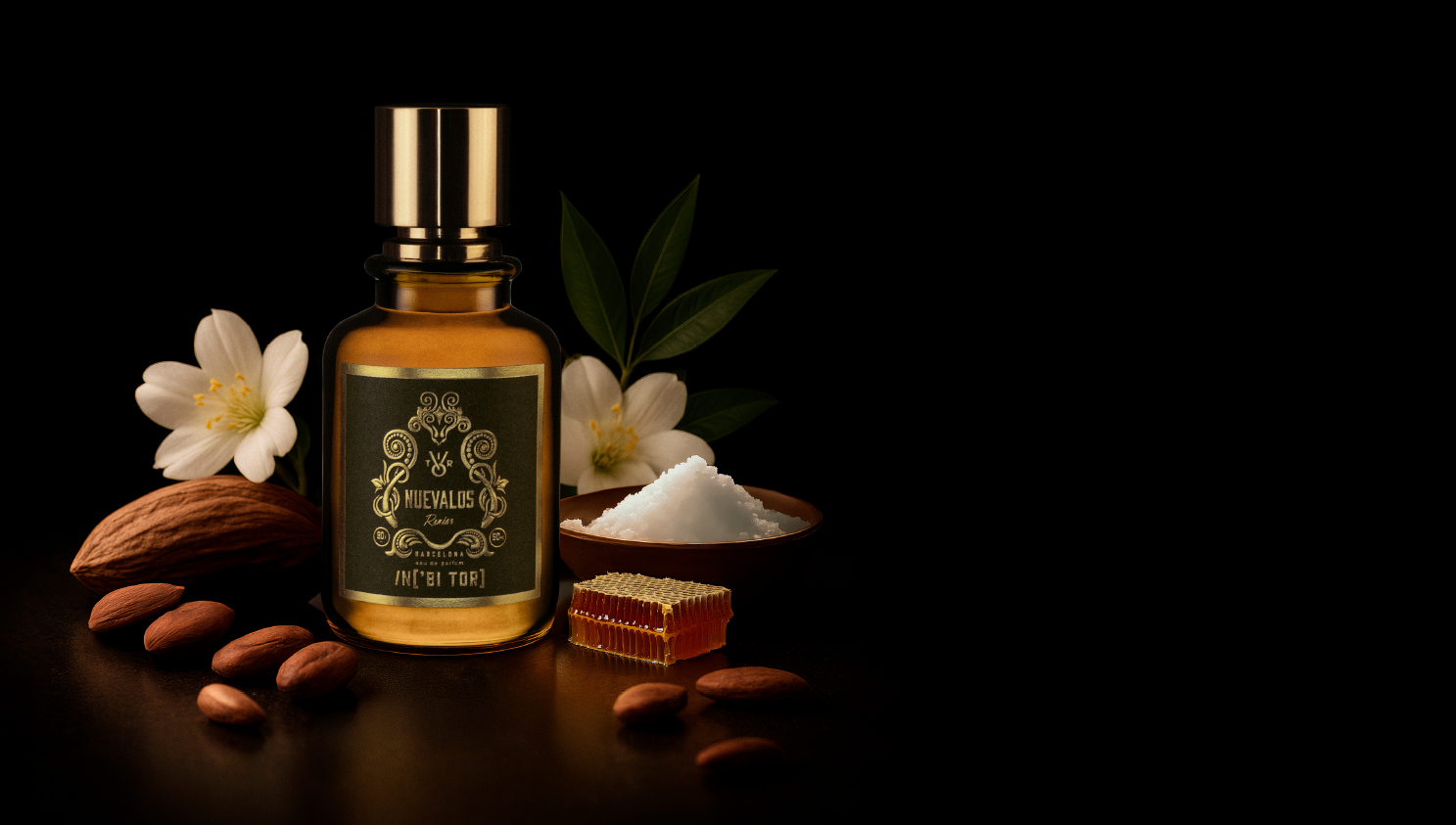 Botella de aceite de color ámbar con tapón dorado, almendras, flores, sal y miel sobre fondo negro.