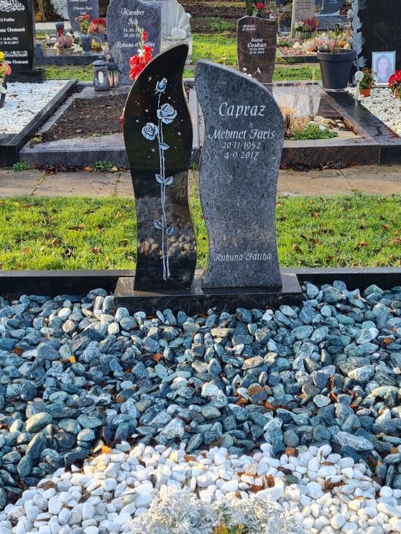 Ein Grab auf einem Friedhof, umgeben von Grabsteinen und Kies.