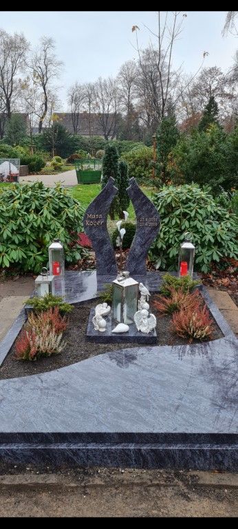 Ein Grab auf einem Friedhof mit Kerzen und Blumen.