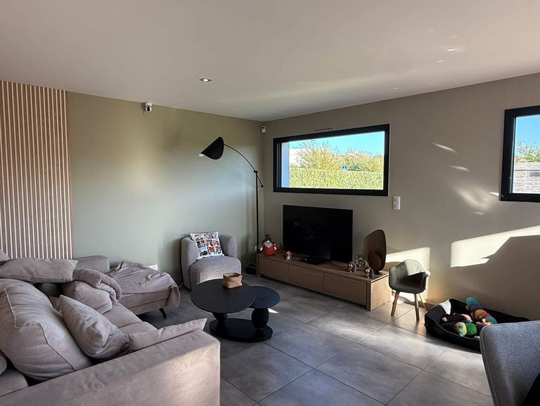 Salon avec téléviseur, table basse, fauteuil, canapé et fenêtres