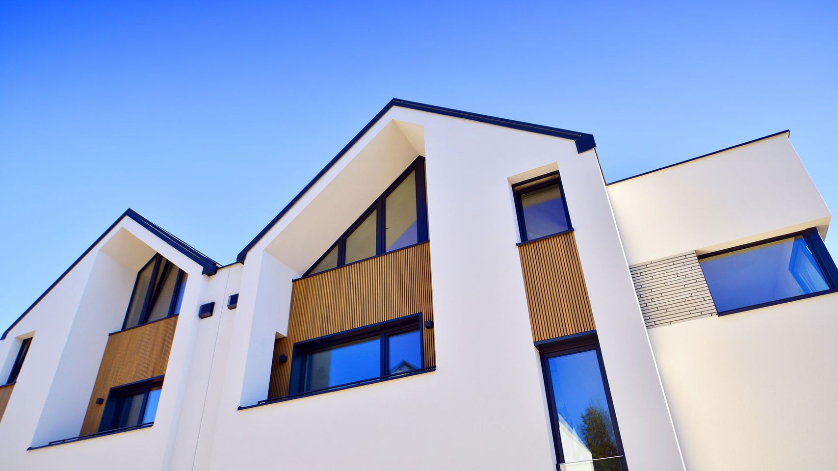 Immeuble beige avec des touches de bleu sur le toit et une tour centrale, en bordure d’une rue