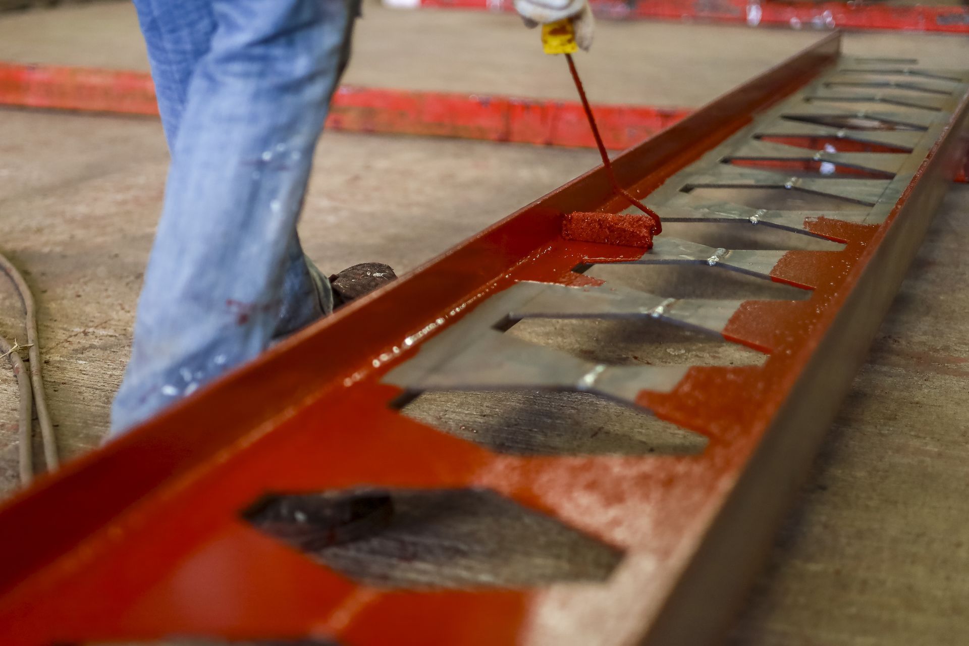 Personne en train de peindre une structure métallique rouge dans un atelier