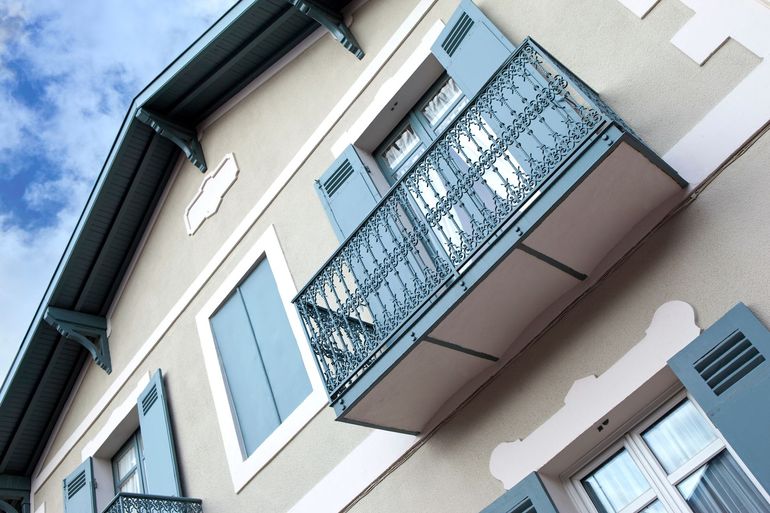 Façade d'une maison avec balcon et volets fraîchement repeints