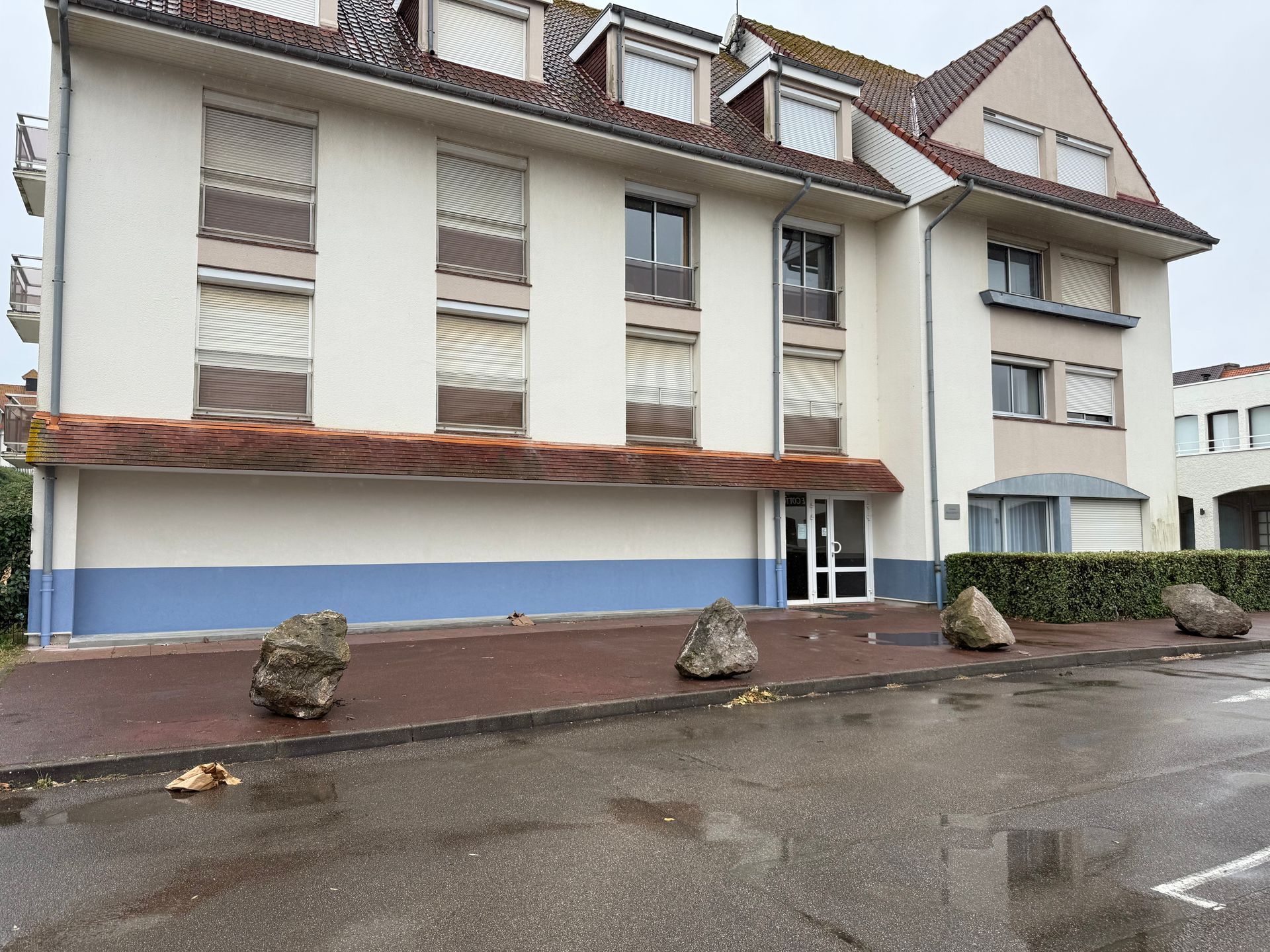Petite maison blanche aux volets et à la porte rouges, dans une rue paisible