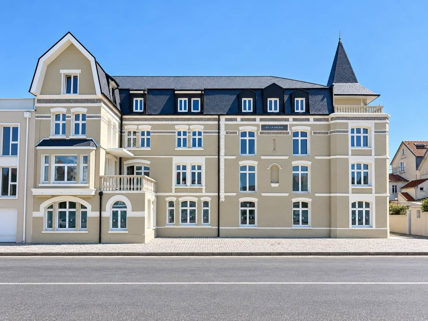 Grand bâtiment à deux étages et à la façade claire après rénovation, sous un ciel bleu