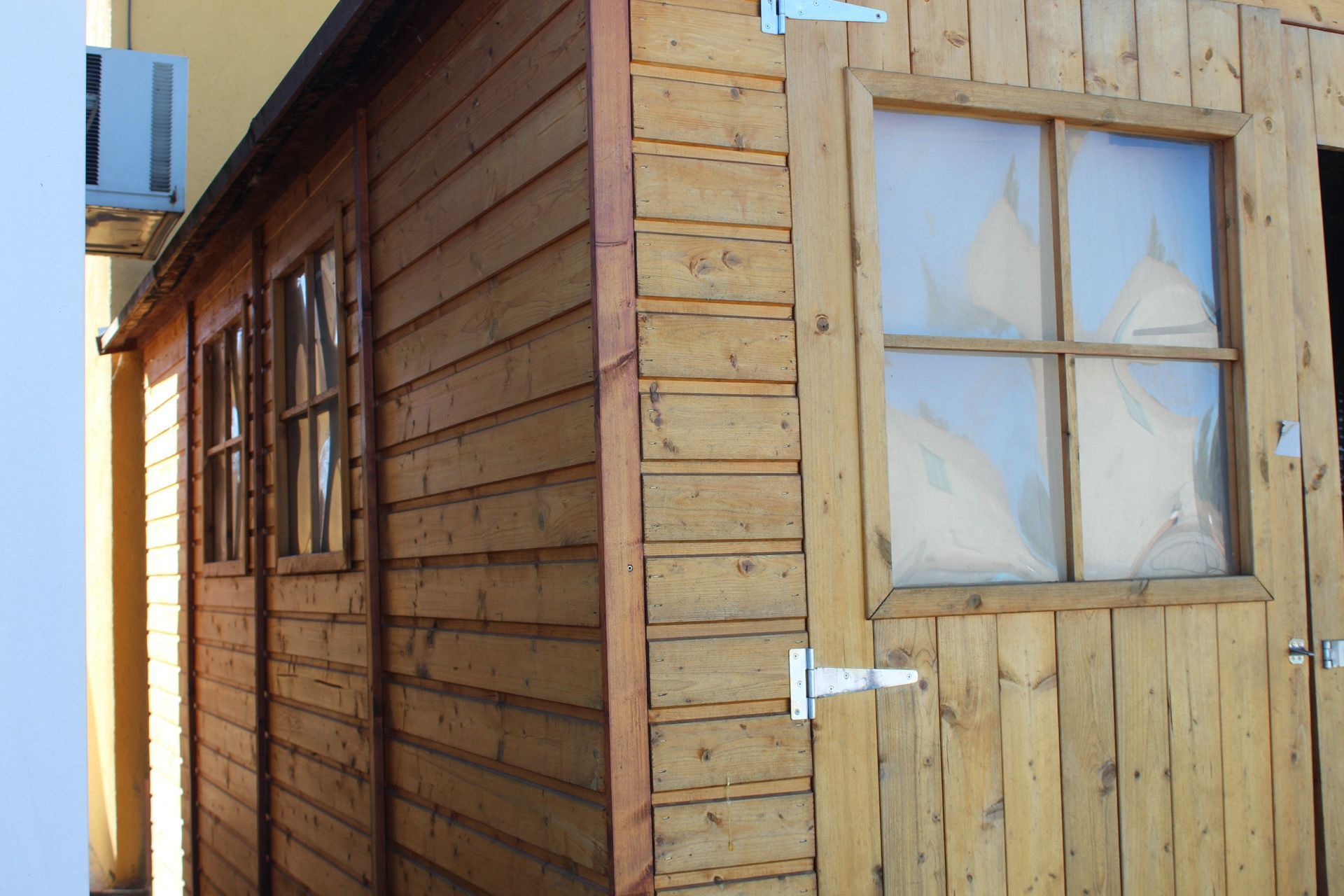 Caseta de madera con varias ventanas y una puerta. Tonos de madera marrón y clara.