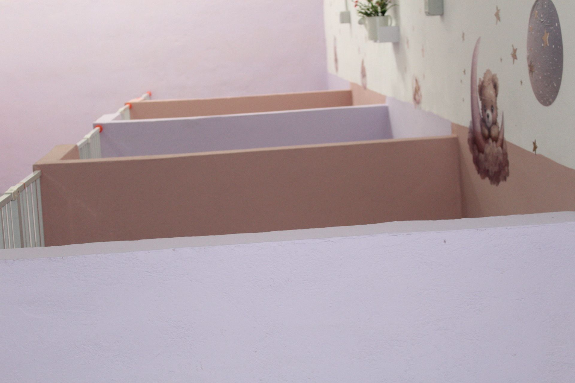 Escalera pintada de blanco y rosa con decoración mural que representa un oso y estrellas.