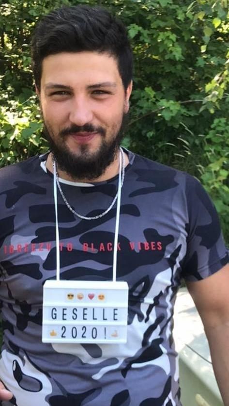 Ein Mann mit Bart hält ein Schild mit der Aufschrift „Geselle 2020“