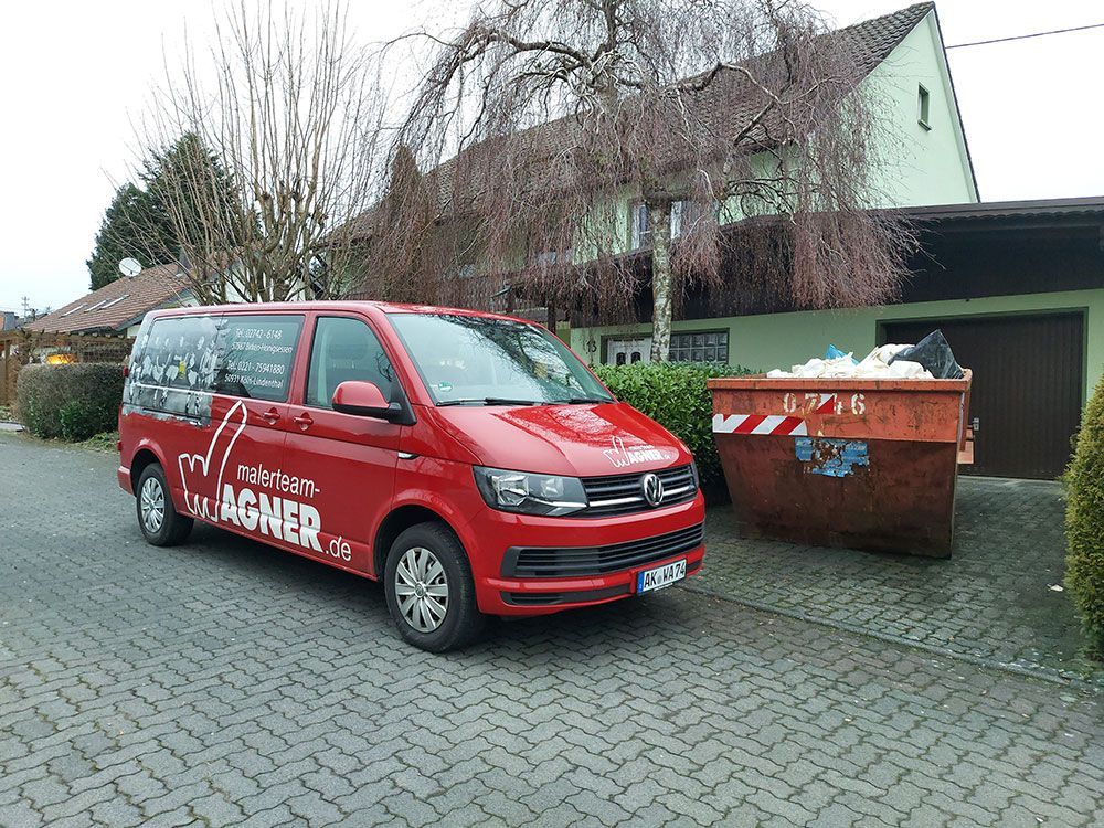 Ein roter Lieferwagen steht vor einem Haus.
