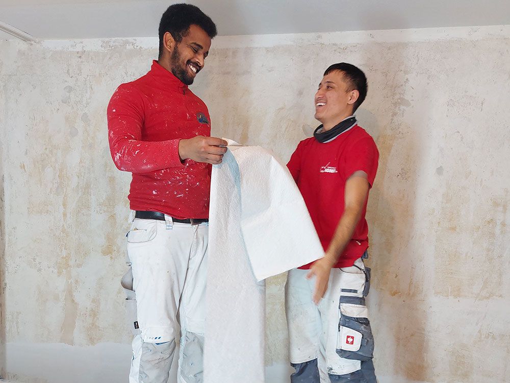 Zwei Männer stehen nebeneinander und halten ein Stück Papier in der Hand.