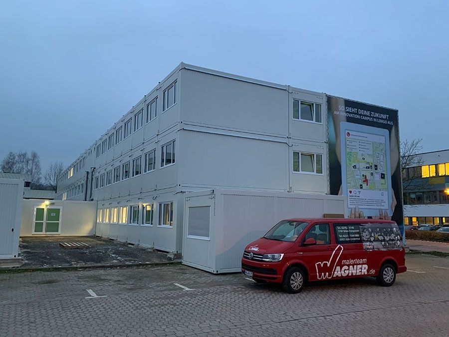 Ein roter Lieferwagen parkt vor einem großen weißen Gebäude.