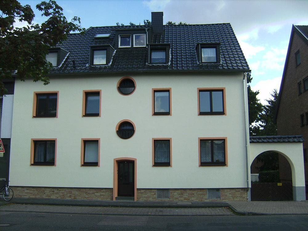 Ein weißes Gebäude mit einem schwarzen Dach und vielen Fenstern