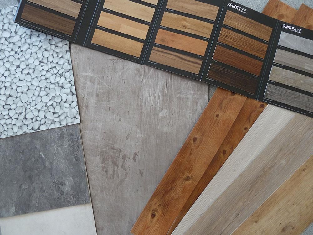 Auf dem Tisch liegen viele unterschiedliche Holzarten und Fliesen.