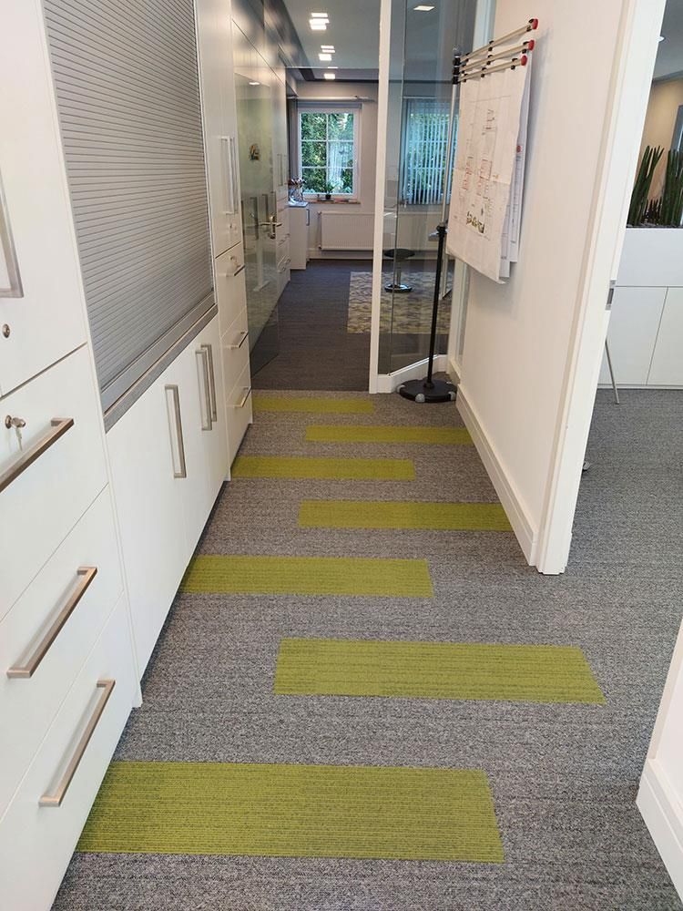 Ein Flur mit einem grün-grauen Teppich und einer weißen Tafel an der Wand.