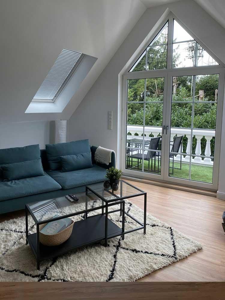 Ein Wohnzimmer mit einem blauen Sofa, zwei Couchtischen und einem Teppich.