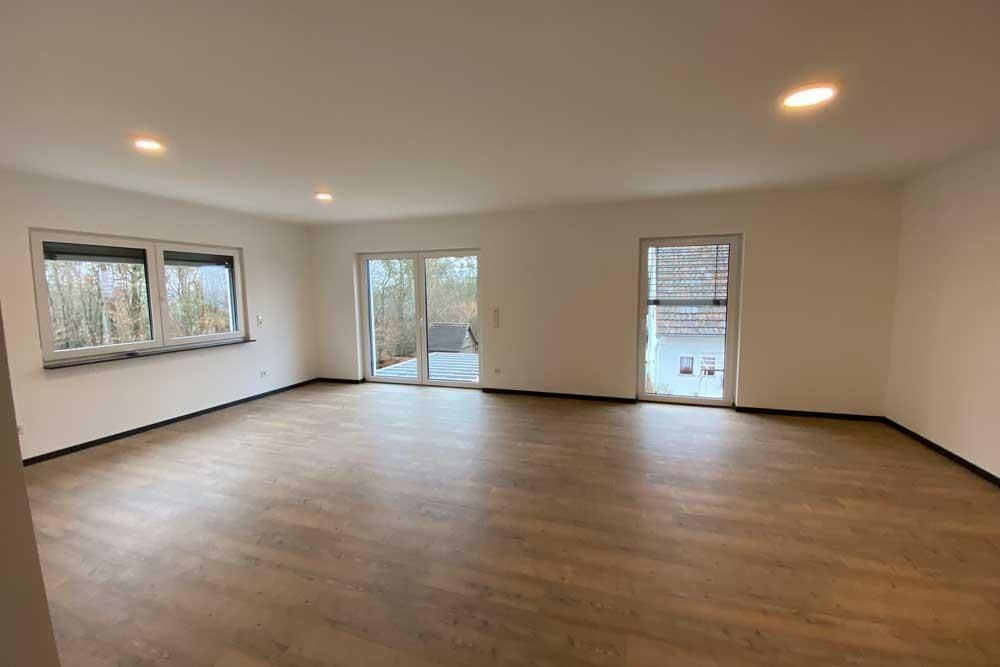 Ein großes leeres Wohnzimmer mit Hartholzböden und weißen Wänden.