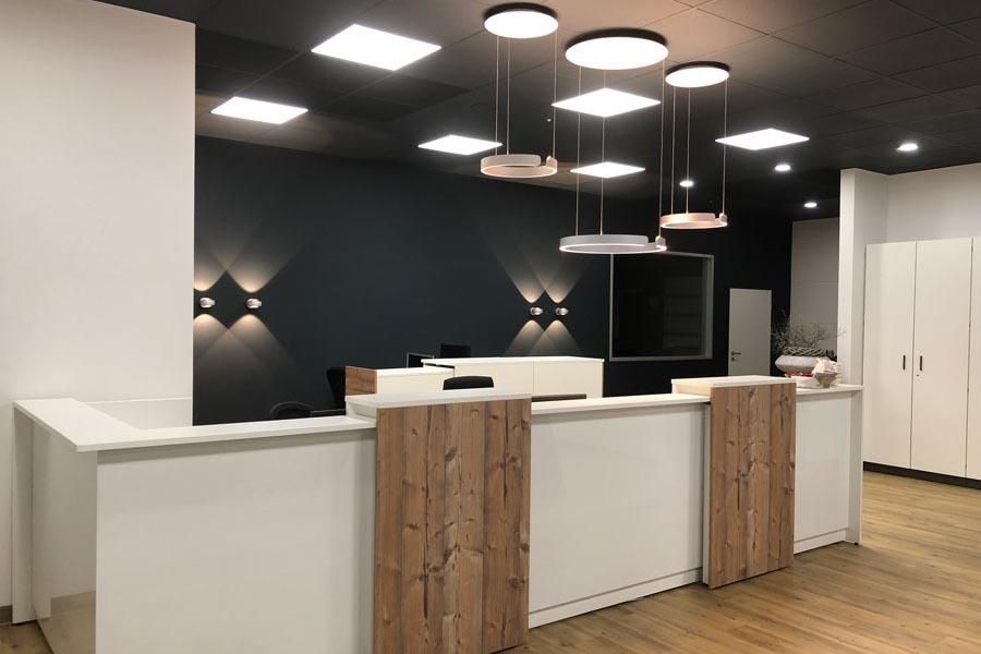 Ein Empfangstresen in einem Raum mit vielen von der Decke hängenden Lampen.