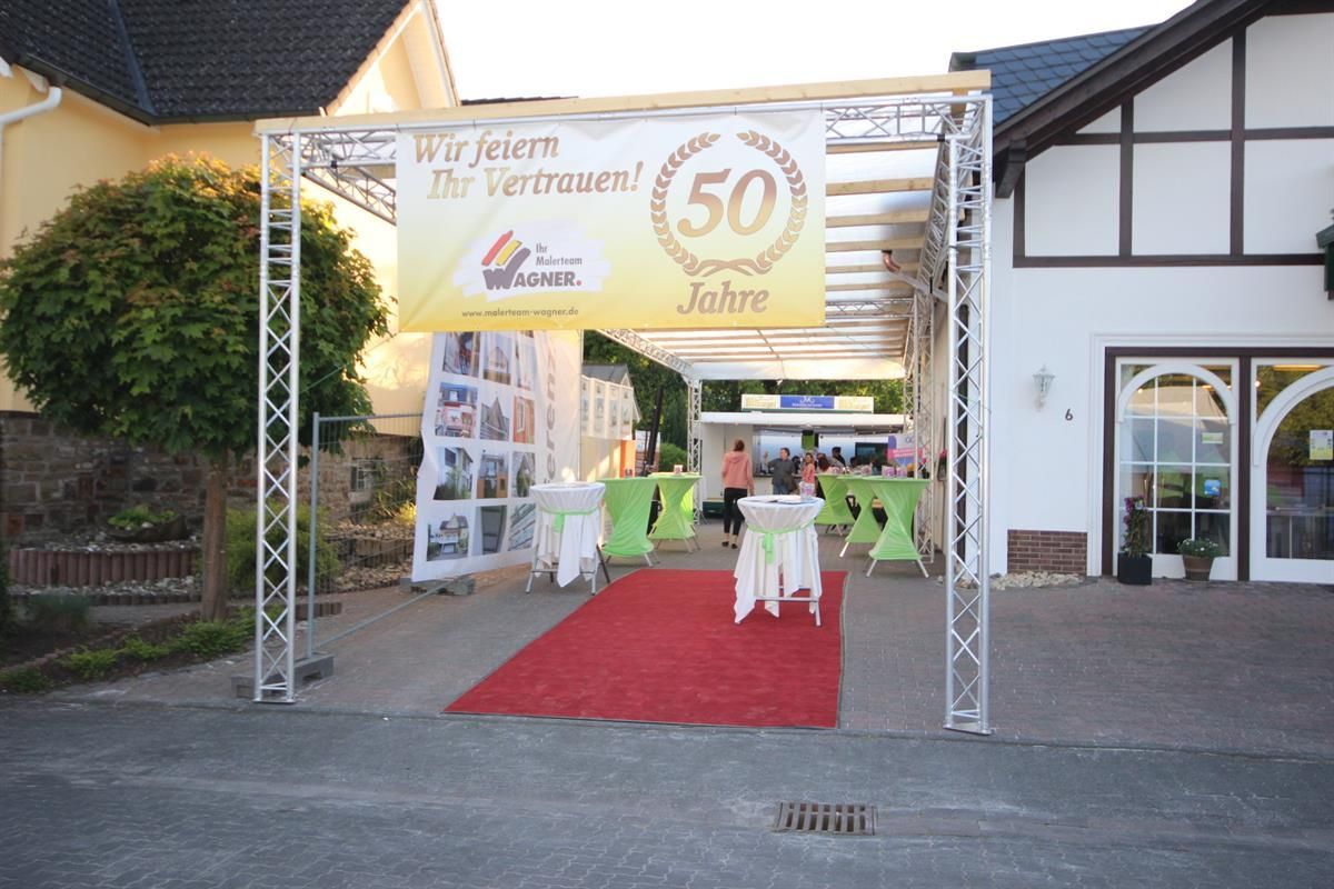 Ein Schild mit der Aufschrift „50 Jahre“ hängt über einem roten Teppich