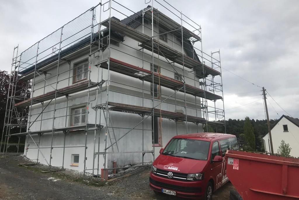 Ein roter Lieferwagen steht vor einem im Bau befindlichen Gebäude.