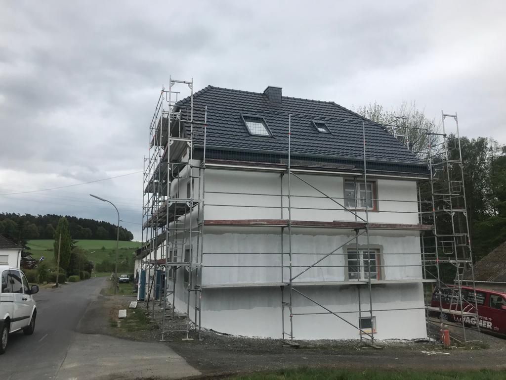 Ein weißer Lieferwagen parkt vor einem im Bau befindlichen Gebäude.