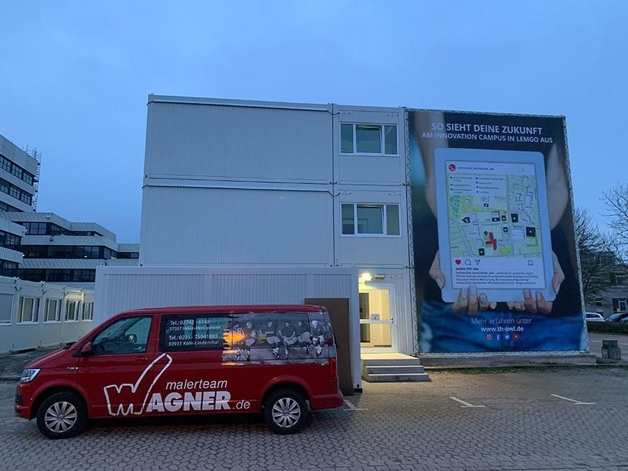 Ein roter Wagner-Van steht vor einem Gebäude