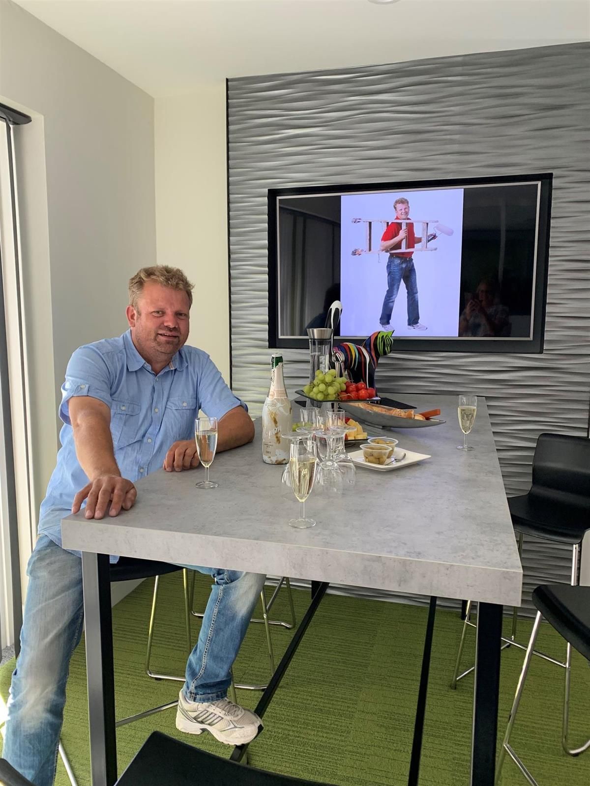 Ein Mann sitzt an einem Tisch vor einem Fernseher.