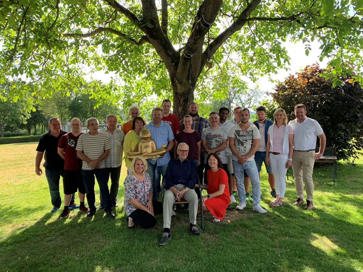Eine Gruppe von Menschen posiert unter einem Baum für ein Foto.