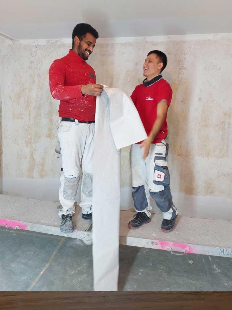 Zwei Männer stehen nebeneinander und halten ein Stück Papier in der Hand.