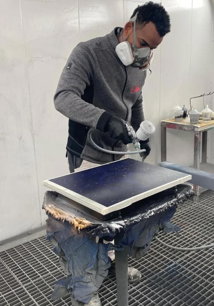 Ein Mann mit einer Maske schleift ein Stück Holz.