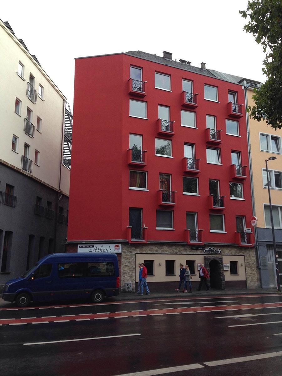 Ein rotes Gebäude mit einem davor geparkten blauen Lieferwagen