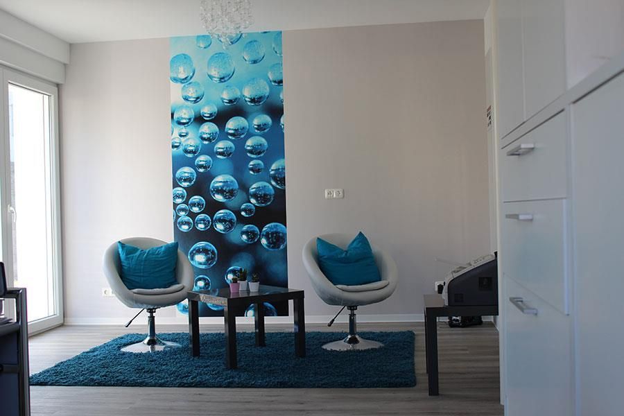 Ein Wohnzimmer mit zwei Stühlen und einem Tisch mit einem Bild von Seifenblasen an der Wand.