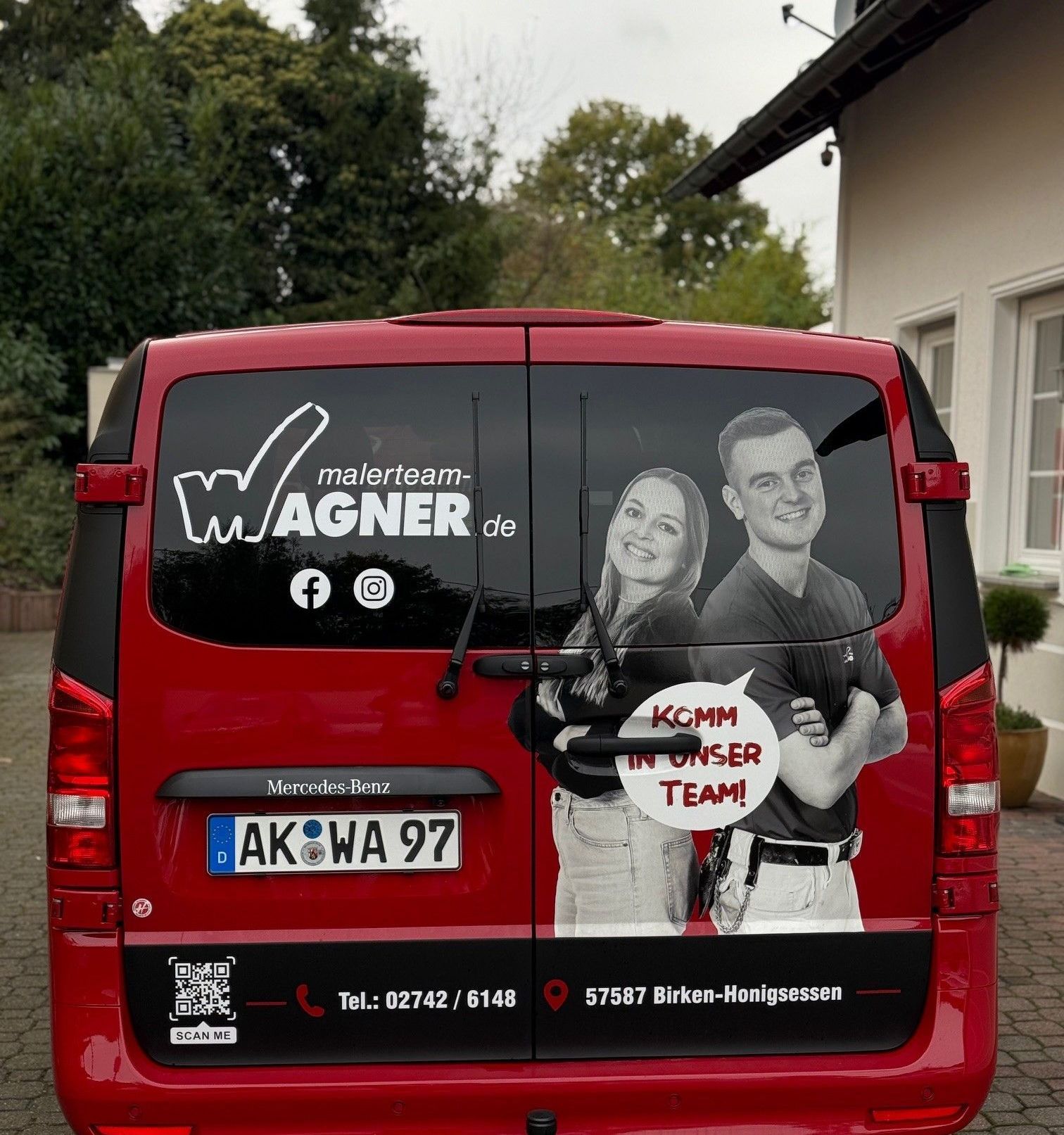 Eine Gruppe von Menschen steht vor einem roten Banner mit der Aufschrift „wagner.de“