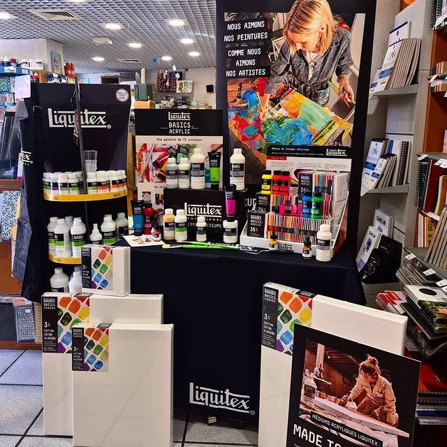 Présentoir de matériel artistique Liquitex en magasin, avec toiles, peintures et articles promotionnels.