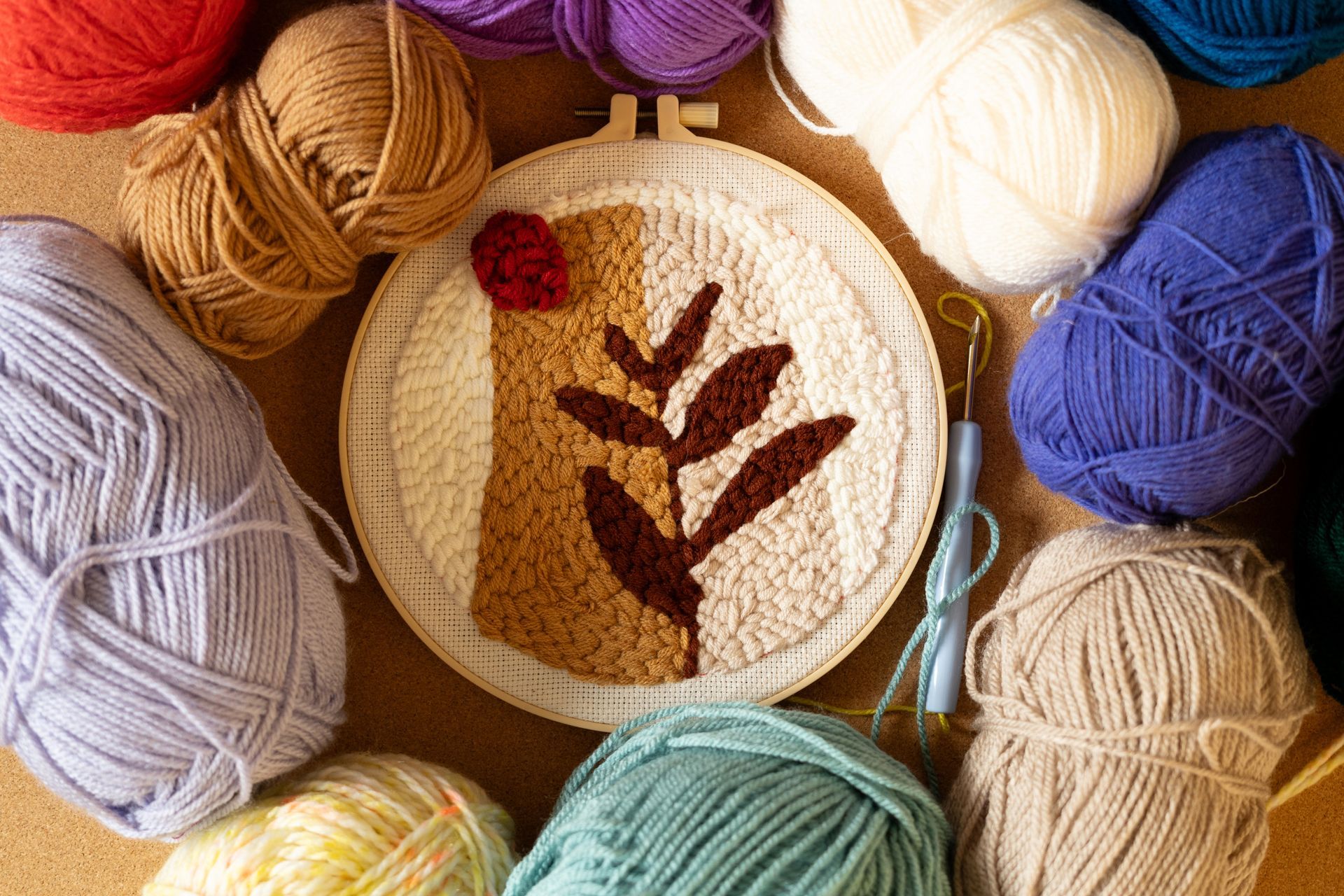 Broderie à l'aiguille à poinçonner dans un cercle en bois entouré d'écheveaux de laine.