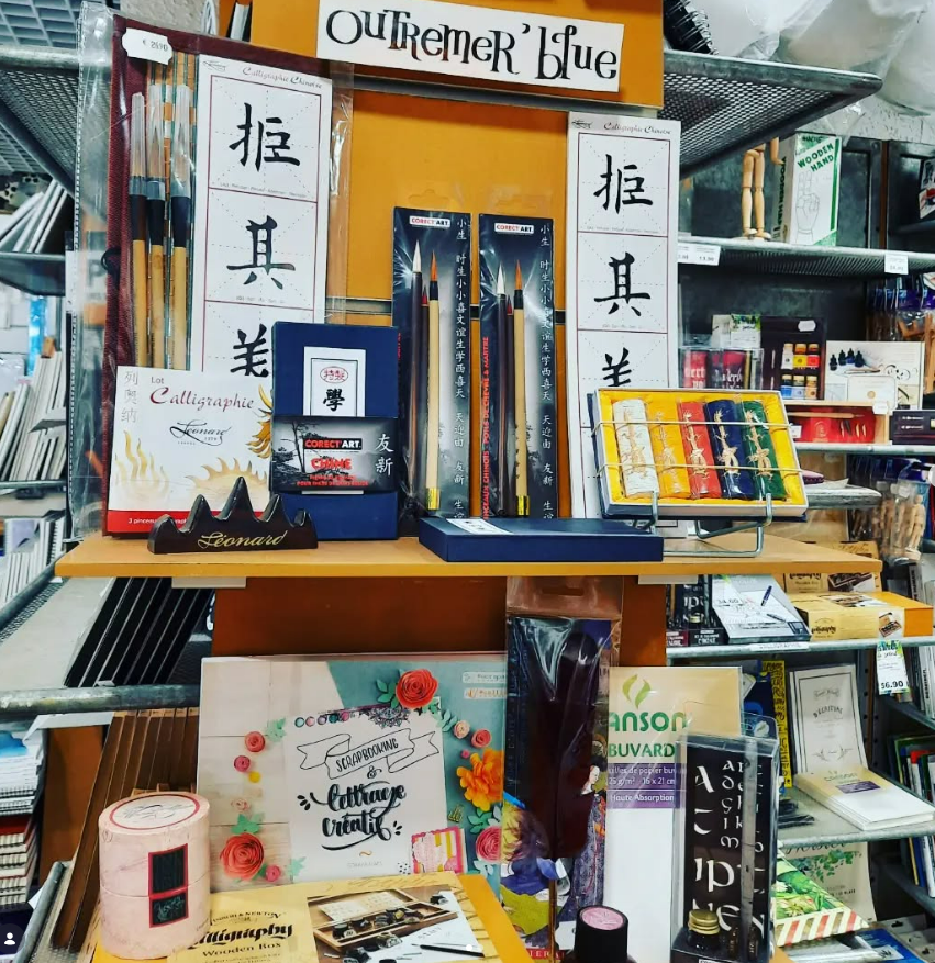 Présentoir de papeterie dans un magasin, présentant des fournitures de calligraphie comme des stylos, de l'encre, du papier et des livres de calligraphie.